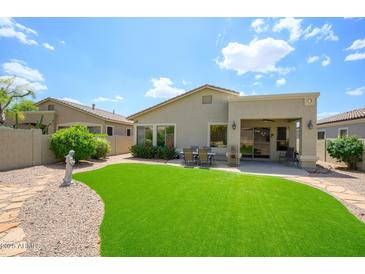 A well-maintained backyard featuring lush artificial turf and a covered patio with outdoor seating, perfect for relaxing at 5014 E Kirkland Rd, Phoenix, AZ 85054