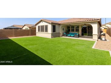 Spacious backyard with artificial turf, desert landscaping, and a covered patio for outdoor living at 6931 W Spur Dr, Peoria, AZ 85383