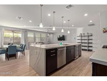 Open-concept kitchen with stainless steel appliances, an island, a nearby dining area and living room at 6931 W Spur Dr, Peoria, AZ 85383