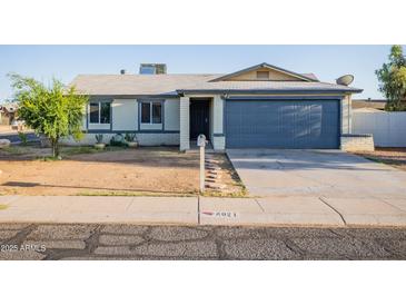 Charming single story home with a well maintained yard, desert landscaping, and a blue garage door at 8021 W Hazelwood St, Phoenix, AZ 85033