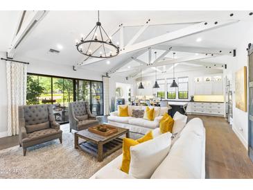 Bright living room with vaulted ceilings, hardwood floors, and open to dining area at 10179 E Camelot Ct, Scottsdale, AZ 85255