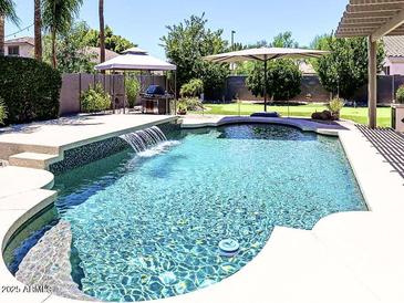 Inviting pool with waterfall feature, complemented by lush landscaping and outdoor amenities at 12753 W Vista Paseo Dr, Litchfield Park, AZ 85340