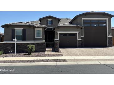 Charming single-Gathering home with a two-car garage and welcoming brick driveway and stone accents at 17427 W Hadley St, Goodyear, AZ 85338