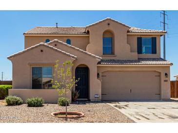 Two-story home with a beige exterior, arched entry, landscaping, and a two car garage at 18663 W Vogel Ave, Goodyear, AZ 85338