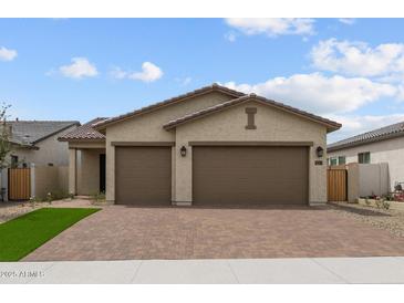Charming single-story home featuring a brick driveway, a three-car garage, and a well-maintained front yard at 19321 W Luke Ave, Litchfield Park, AZ 85340
