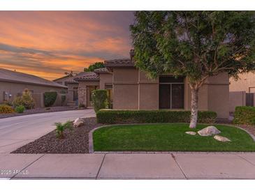 Charming home featuring lush landscaping, verdant lawn, a stone accent wall, and a circular driveway at 712 W Jade Dr, Chandler, AZ 85248