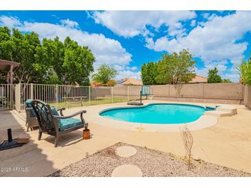Inviting backyard pool with stone patio, lush greenery, and comfortable seating, perfect for relaxation and entertainment at 10566 E Bogart Ave, Mesa, AZ 85208