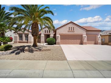 Charming single-story home featuring a three-car garage, mature palm trees, and low-maintenance desert landscaping at 16158 W Copper Point Ln, Surprise, AZ 85374
