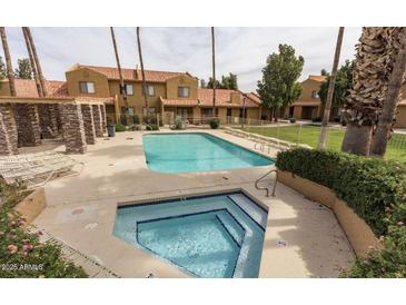Exterior shot of pool and hot tub, surrounded by landscaped grounds and multi-story condo complex in the background at 3511 E Baseline Rd # 1235, Phoenix, AZ 85042