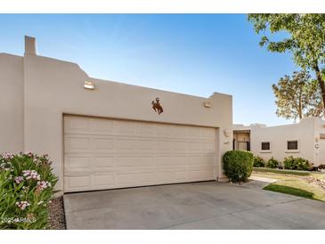 Neutral garage door with bronco art matches the home's southwestern aesthetic in front of manicured landscaping at 5445 E Mckellips Rd # 23, Mesa, AZ 85215