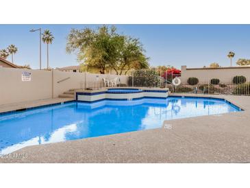 Community pool area with a jacuzzi, surrounded by desert landscaping and security fencing at 5445 E Mckellips Rd # 23, Mesa, AZ 85215