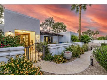 Charming courtyard entrance with wrought iron gate and lush desert landscaping at 6112 E Jenan Dr, Scottsdale, AZ 85254
