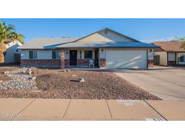 Charming single-story home featuring desert landscaping, a two-car garage, and a welcoming front porch at 6311 E Ivy St, Mesa, AZ 85205