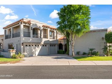 Beautiful two-story home featuring a three-car garage and a well-manicured front yard with a large tree at 8429 E Del Camino Dr, Scottsdale, AZ 85258