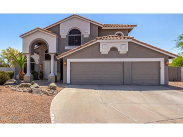 Two-story home with a gray exterior, a tiled roof, and a three-car garage showcasing its attractive curb appeal at 9203 E Topeka Dr, Scottsdale, AZ 85255
