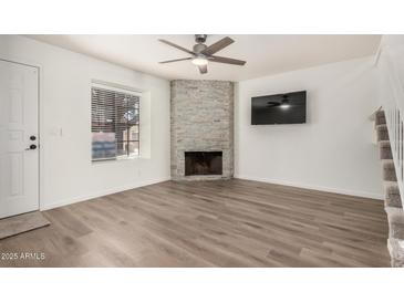 Inviting living room showcasing a stone fireplace, wood floors, and a contemporary ceiling fan at 921 W University Dr # 1038, Mesa, AZ 85201