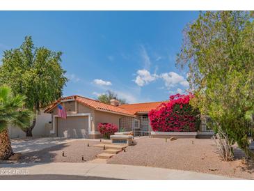 Inviting one-story home with a lush garden, desert landscaping, and a two-car garage at 10580 E Bella Vista Dr, Scottsdale, AZ 85258