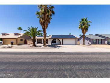 Charming single-story home with solar panels and desert landscaping, including palm trees at 10610 W Diana Ave, Peoria, AZ 85345