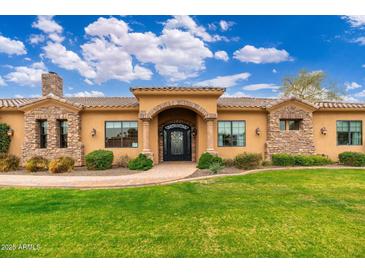 Charming home exterior showcasing beautiful stonework, lush green lawn, and an inviting front entrance at 13206 N 64Th St, Scottsdale, AZ 85254