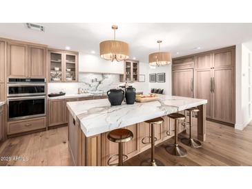 Bright kitchen features a marble waterfall island, stainless steel appliances, and custom wood cabinetry at 16227 N 63Rd Pl, Scottsdale, AZ 85254