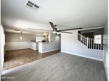 Bright living room has a ceiling fan and overlooks the kitchen and staircase at 37061 W Bello Ln, Maricopa, AZ 85138