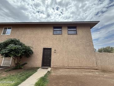 Charming two-story townhouse with stucco exterior, front door, and green shrubbery in the front yard at 4231 N 69Th Dr # 1297, Phoenix, AZ 85033