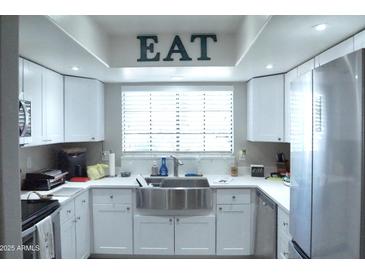 Modern kitchen with white cabinets, stainless steel appliances, and a farmhouse sink at 6885 E Cochise Rd # 127, Paradise Valley, AZ 85253