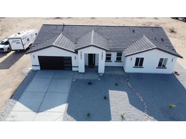 Aerial view of new construction featuring a neutral colored stucco, gray roof, and modern garage door at 11798 S 216Th Ave, Buckeye, AZ 85326