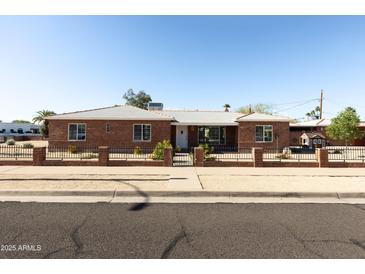 Charming red brick home features a tidy yard enclosed with a black decorative metal fence at 1330 E Monte Vista Rd, Phoenix, AZ 85006
