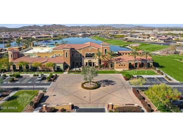 Stunning aerial view of the community clubhouse with a lake, lush landscaping, and mountains in the background at 17900 W Briarwood Dr, Goodyear, AZ 85338