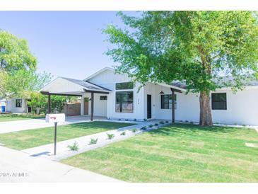 Beautifully renovated home with a well-manicured lawn, modern white paint, and stylish black accents at 214 W Ruth Ave, Phoenix, AZ 85021