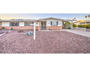 Charming single-story home with a low brick wall and desert landscaping featuring gravel and sparse vegetation at 10620 W Clair Dr, Sun City, AZ 85351