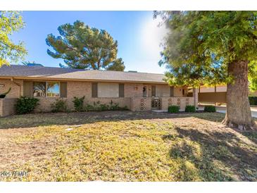 Charming single-story brick home featuring well-maintained landscaping and mature trees at 13823 N 99Th Dr, Sun City, AZ 85351