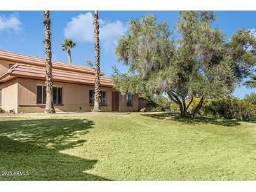 Charming home featuring a lush lawn, mature trees, and a classic tiled roof under a bright blue sky at 14401 N Boxwood Ln, Fountain Hills, AZ 85268