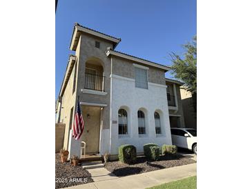 Charming two-story home featuring stucco siding, arched windows, and a welcoming entrance with an American flag at 1448 E Mobile Ln, Phoenix, AZ 85040