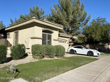 Well maintained home with green lawn, mature trees, and a white sports car in the driveway at 2042 W Periwinkle Way, Chandler, AZ 85248