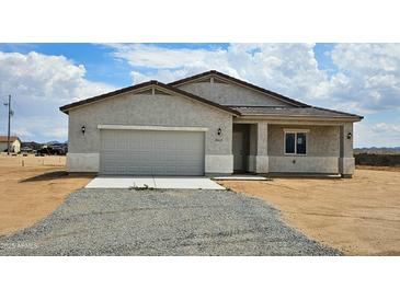 Charming single-story home featuring a neutral color, a two-car garage and a well-maintained desert landscape at 20435 W Mountain Sage Dr, Buckeye, AZ 85326