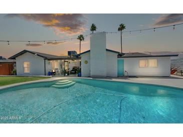 Tranquil backyard showcasing a sparkling pool, lush greenery, and an inviting outdoor living space at sunset at 2820 E Surrey Ave, Phoenix, AZ 85032