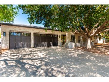 Stunning home exterior with a three-car garage, brick driveway and lush tree providing ample shade at 5440 E Calle Camelia --, Phoenix, AZ 85018