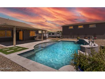 Inviting backyard pool and patio area with outdoor kitchen, perfect for entertaining and relaxation with a stunning sunset at 18319 W Marshall Ave, Litchfield Park, AZ 85340