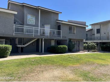 Low-rise apartment building with dark gray exterior, second story balconies and green lawn at 19601 N 7Th St Ave # 1036, Phoenix, AZ 85024