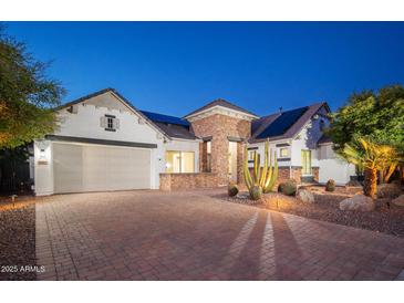 Charming single-Gathering home featuring desert landscaping, solar panels, and a paver driveway at 7590 W Firebird Dr, Glendale, AZ 85308