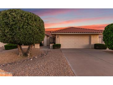 Charming home with a two-car garage, desert landscaping, and a red tile roof in front of a colorful sunset at 9809 W Behrend Dr, Peoria, AZ 85382