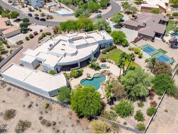 Expansive estate with a unique architecture, pool and tennis courts nestled in lush landscaping and desert surroundings at 11717 E Estrella Ave, Scottsdale, AZ 85259