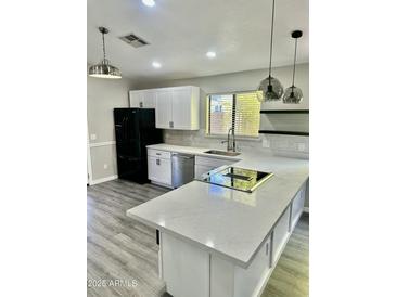 This updated kitchen features gray-tone wood floors, white cabinetry, and a modern island cooktop at 2138 E Williams Dr, Phoenix, AZ 85024