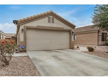 Beige two-car garage with a concrete driveway and low maintenance desert landscaping at 24009 W Antelope Trl, Buckeye, AZ 85326