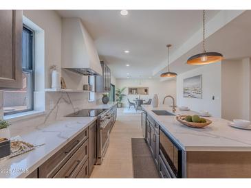 Modern kitchen with stainless steel appliances, large island and marble countertops at 5525 E Waltann Ln, Scottsdale, AZ 85254