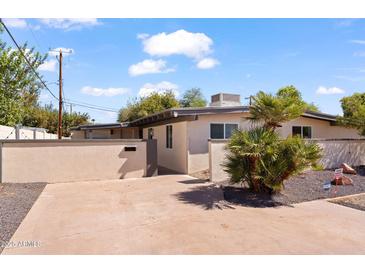 Tan-colored home exterior with a landscaped yard and gray trim around the windows at 5833 N 10Th St, Phoenix, AZ 85014