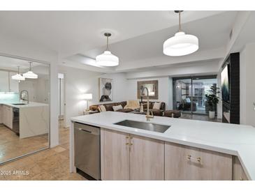 Modern kitchen featuring stone countertops, stainless steel appliances, and pendant lighting, seamlessly flowing into the living area at 7137 E Rancho Vista Dr # 3007, Scottsdale, AZ 85251
