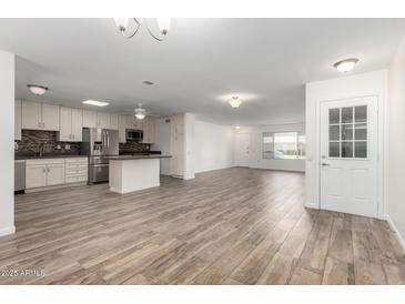 Open-concept living space featuring tile floors, neutral paint, and modern stainless steel appliances at 9863 W Country Club Ct, Sun City, AZ 85373